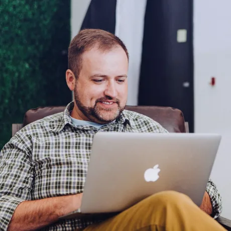 A developer smiling while working on his laptop